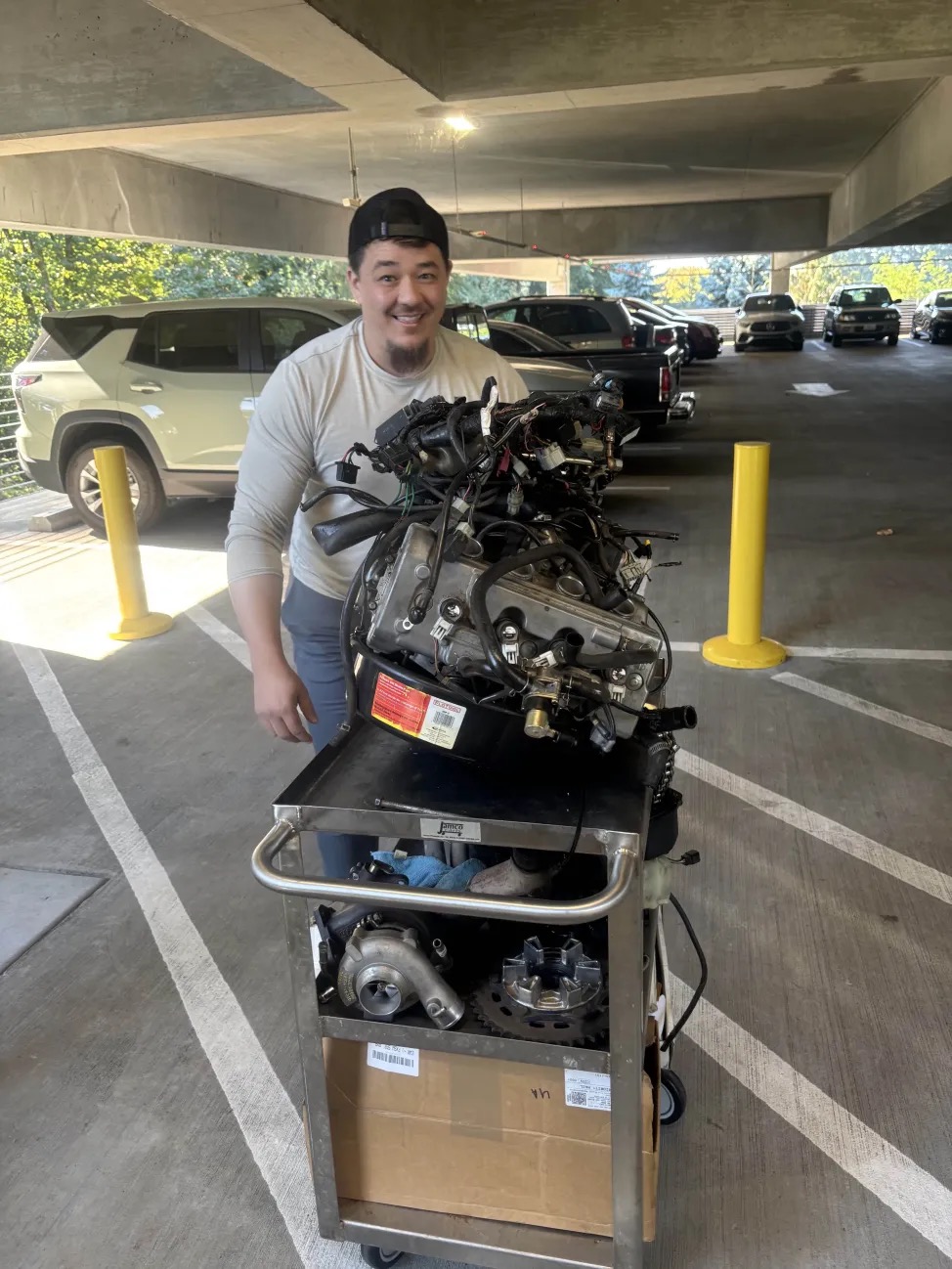 A person happily standing with a cart full of parts.