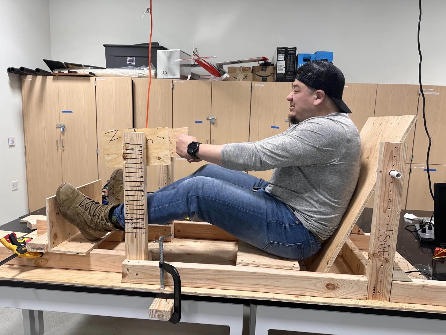 A person sitting in a wooden race car structure.